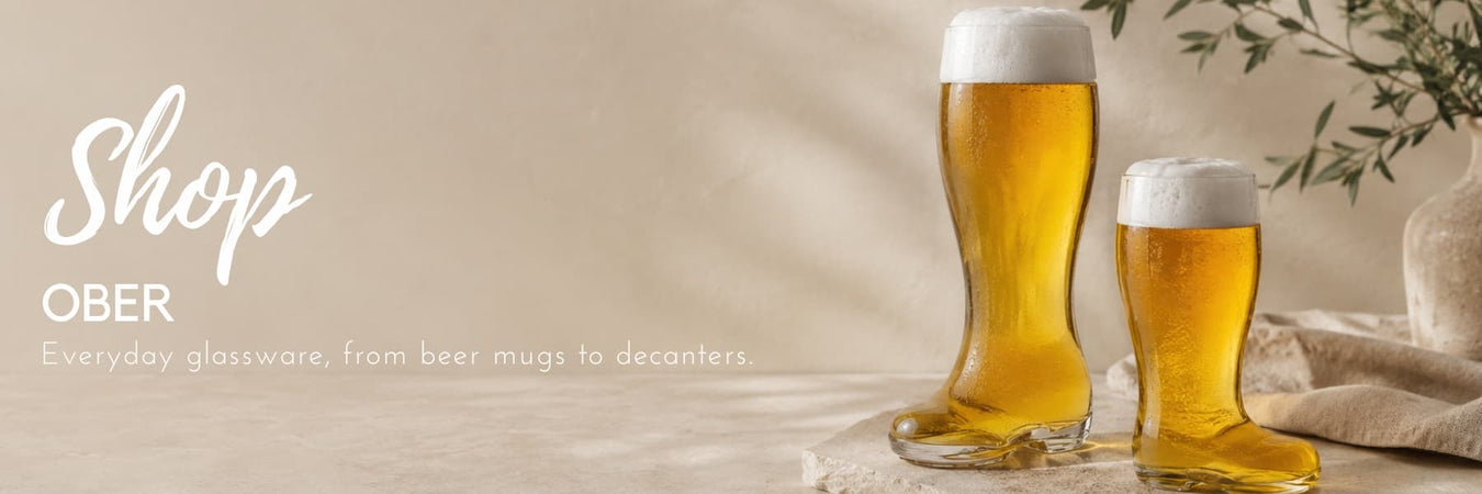 Ober glassware featuring distinctive beer glasses filled with golden lager, styled in a warm, contemporary setting. Everyday glassware designed for relaxed entertaining and celebrations.