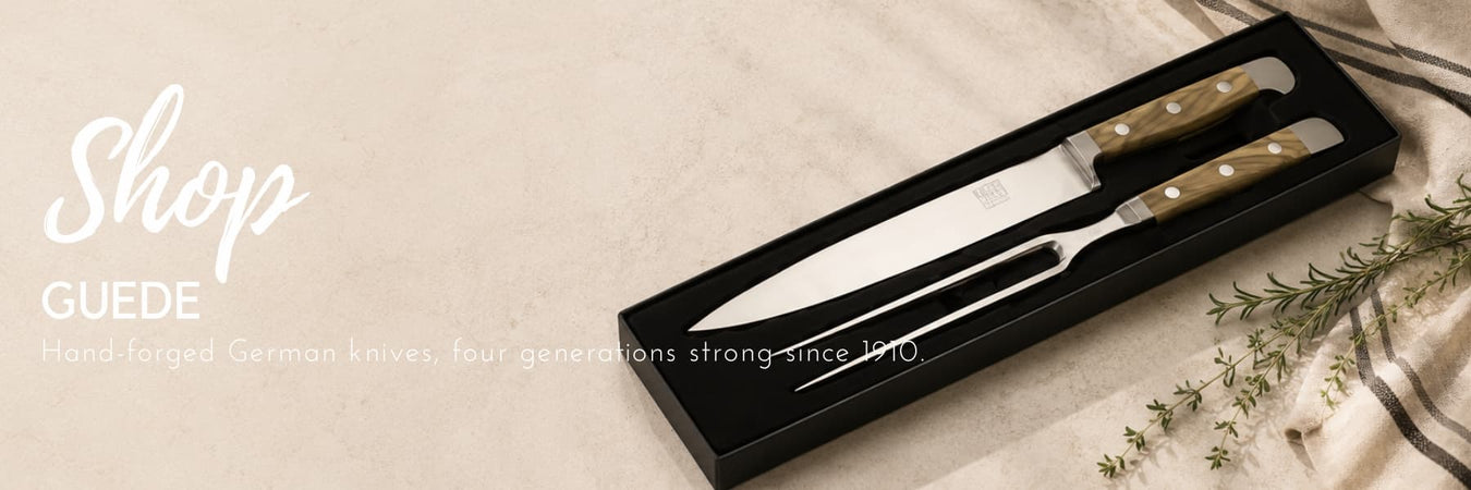 Güde hand-forged German carving knives presented in a premium gift box, styled with natural textures and fresh herbs. Precision-crafted kitchen tools backed by four generations of craftsmanship.