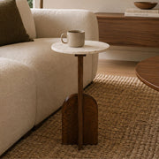 A small round side table with a white marble top and a dark wood base shaped like a shovel, styled in a living room next to a beige sofa with a mug on top - Lighting.co.za