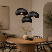 Three black textured pendant lights hanging over a round wooden dining table in a warm, modern interior setting - Lighting.co.za