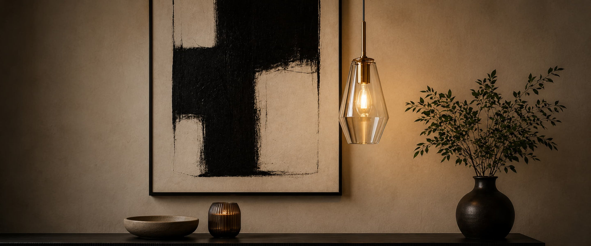 Modern interior with abstract art, Gold and Clear glass pendant light, and decorative items on a shelf.