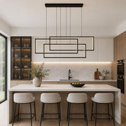 Modern kitchen interior with a black multi-light linear pendant chandelier hanging above a white marble island, four white bar stools, light wood cabinetry, and built-in appliances - Lighting.co.za