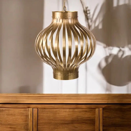 A hanging pendant light with a metallic gold finish and a ribbed, openwork lantern-like shade, shown above a wooden cabinet against a softly lit wall - Lighting.co.za