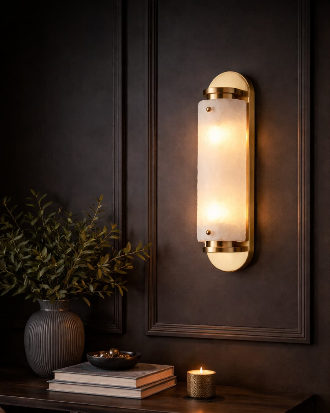 Wall-mounted Gold and Frosted Glass light fixture on a dark wall with a plant and books on a table below. Moody Interior Design Style - Lighting.co.za