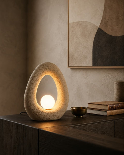 Decorative table lamp with a textured design on a wooden table, with a abstract art piece in the background. - Lighting.co.za