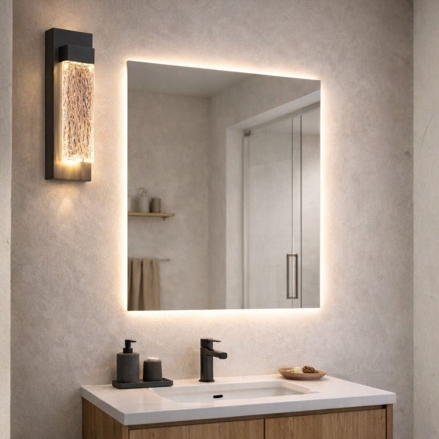 Bathroom vanity with illuminated mirror and wall light fixture.