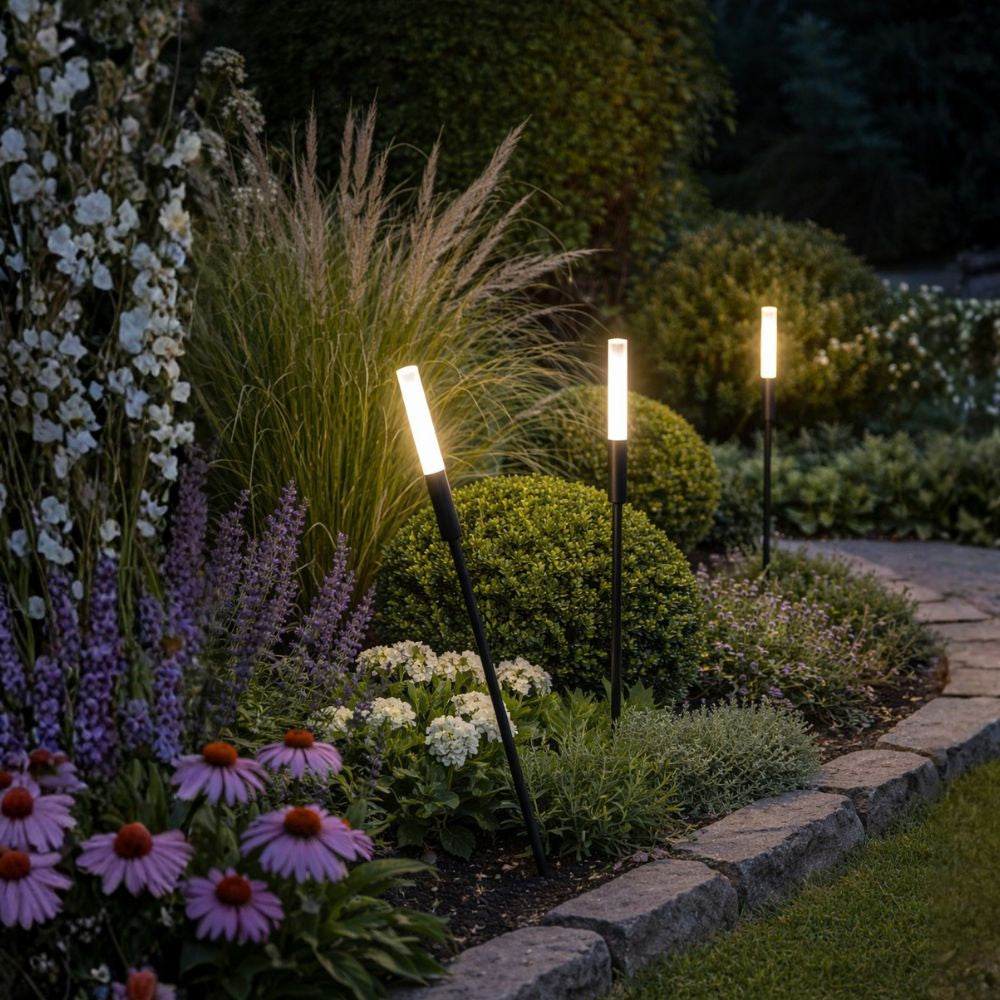 Garden lights illuminating a well-maintained garden with flowers and plants at night. Outdoor Lighting Buying Guide - Lighting.co.za