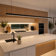 Modern kitchen interior with a large white marble island, black faucet, built-in black appliances, wood cabinetry, and a long black linear pendant light above the counter - Lighting.co.za
