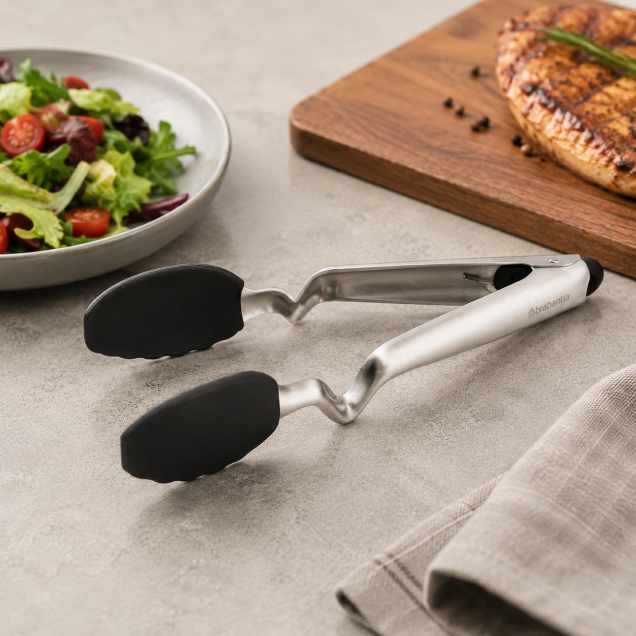 Set of kitchen utensils including tongs, whisks and spatulas in a countertop holder